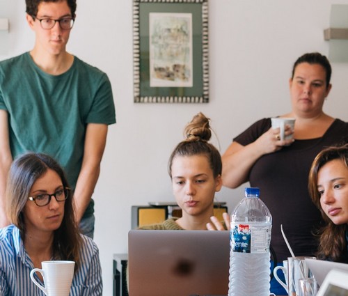 Plusieurs personnes sont en cercle et regarde vers un écran