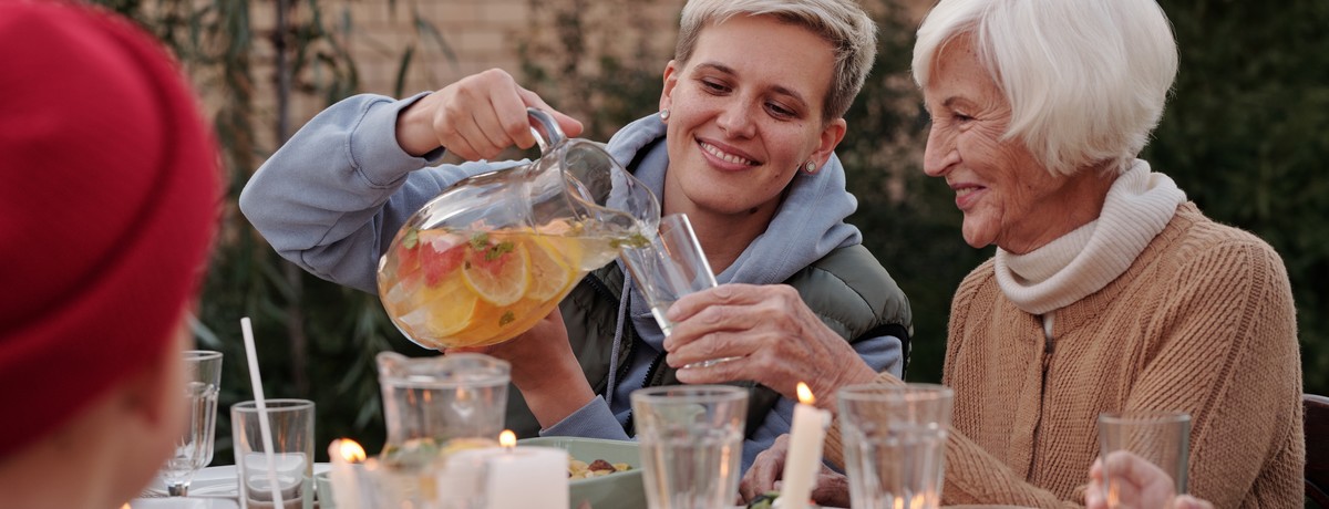 Une femme sert un verre de limonade à une femme plus âgée autour d'une table